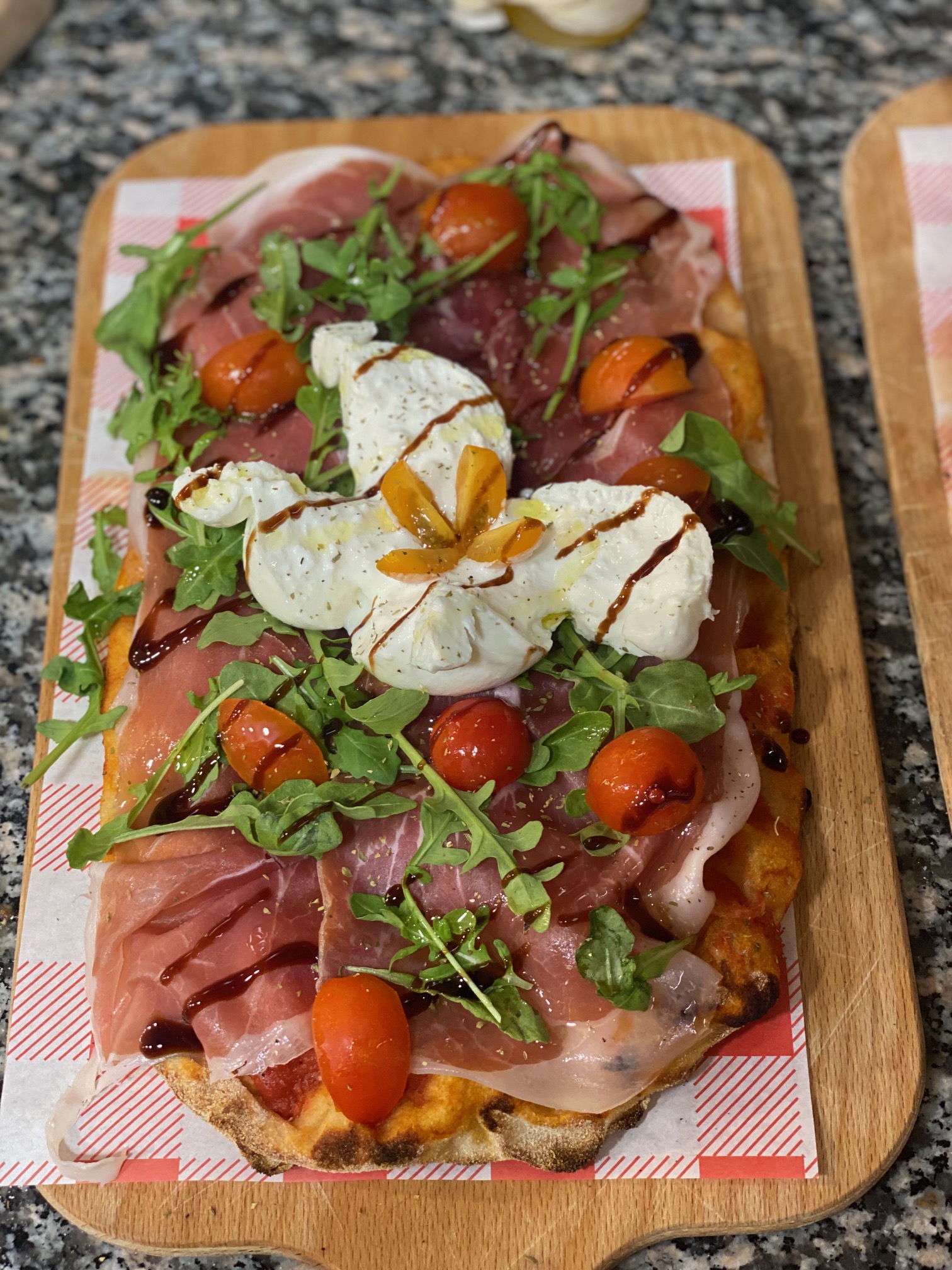 pinsa romana garnie de jambon cru, tomates cerises et mozzarella fraiche