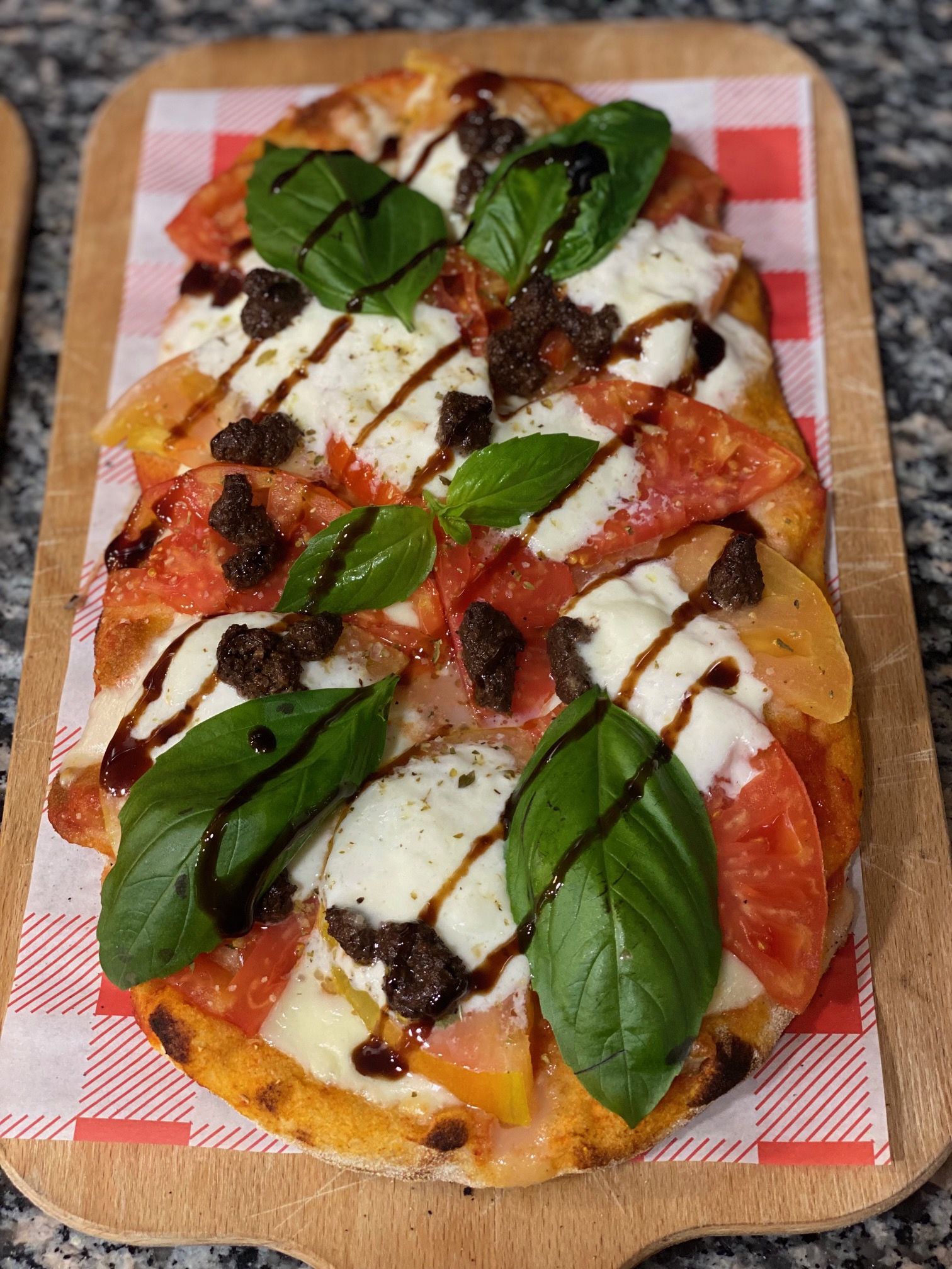 pinsa romana garnie de mozzarella, tomates, basilic et tapenade d'olive noire
