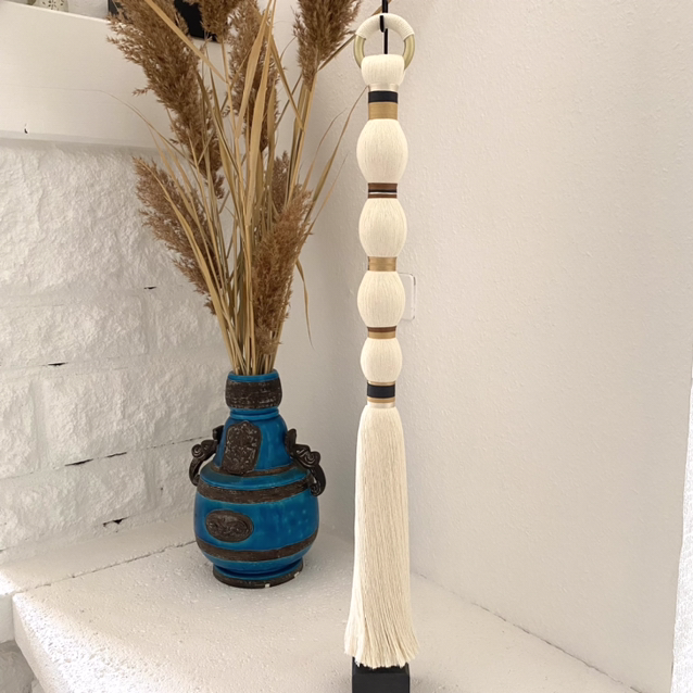 objets décoratifs, l'un ressemble à un vase d'un bleu très pimpant dans lequel sont installées des plantes séchées, l'autre est un assemblage vertical de cordelettes et d'anneaux métalliques