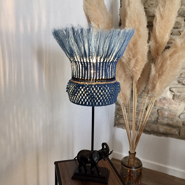 une lampe avec un abbat-jour fabriqué à base de fibres bleues tissées, le pied figure une scuplture d'éléphant
