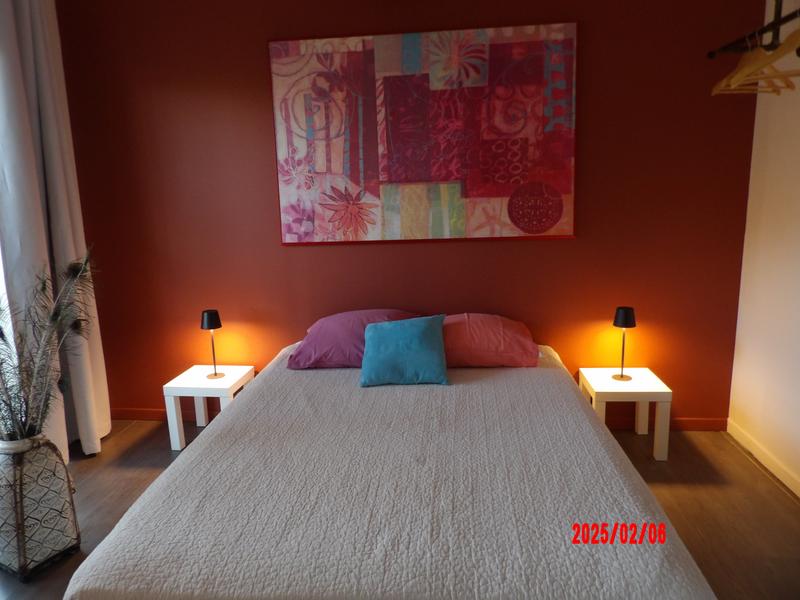 Une chambre à coucher moderne avec un lit double, deux tables de chevet avec lampes, une grande œuvre d'art abstraite sur le mur et un vase décoratif.