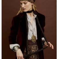 Élégante silhouette bohème chic : blouse blanche fluide, ceinture dorée travaillée, jupe aux motifs baroques et accessoires raffinés.