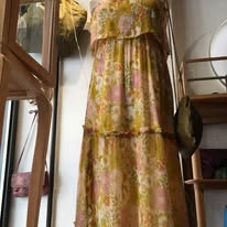 Robe longue fluide aux tons jaunes et orangés, imprimée de motifs floraux pour une allure bohème et ensoleillée.