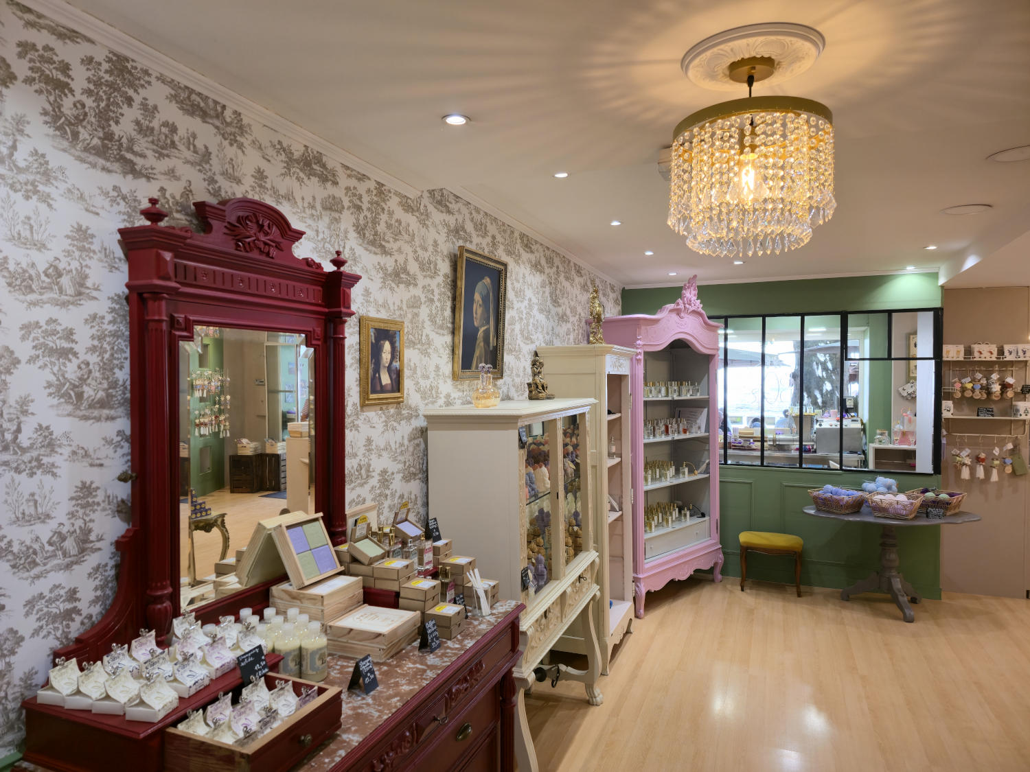 Intérieur d'une boutique décorée dans un style classique, avec un grand miroir rouge, des meubles élégants et des produits exposés.