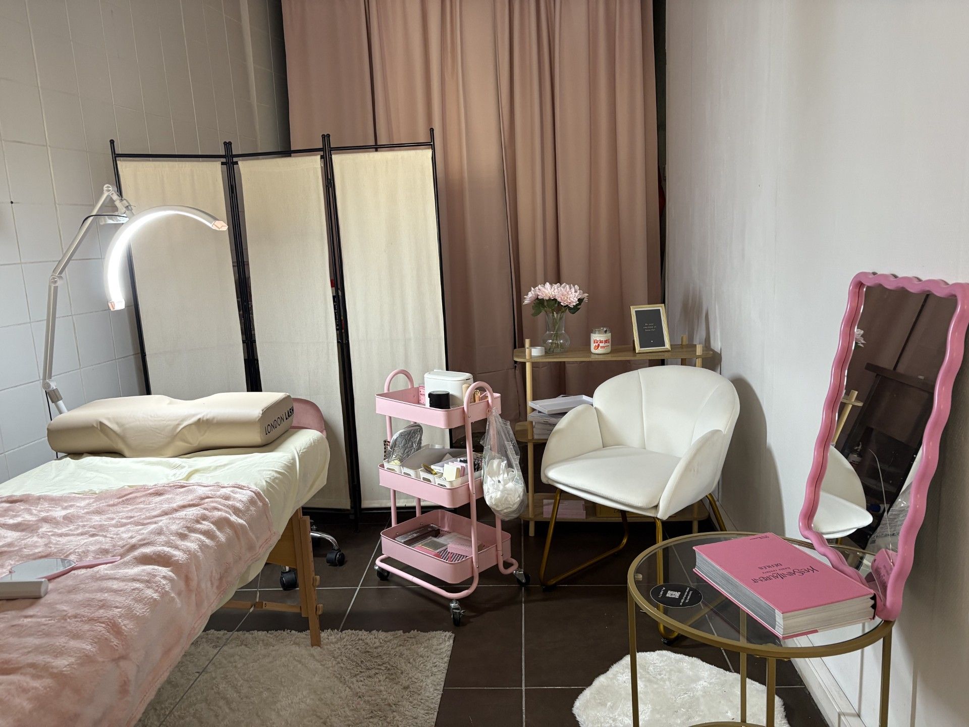 coi esthéthique avec paravent et fauteuil blanc, desserte rose et table pour s'allonger
