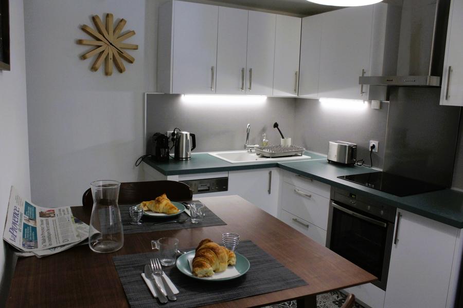 cuisine blacnhe et alu et table bois moderne, 2 sets de tables gris avec assiettes avec croissants 