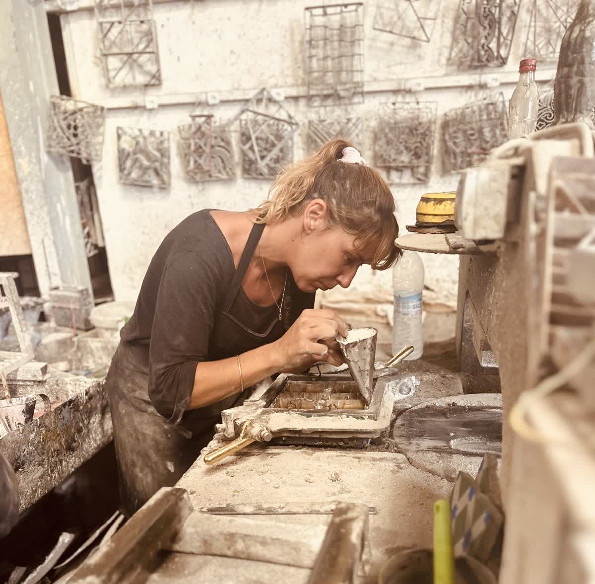 Une artisane travaille minutieusement au remplissage d’un moule lors de la fabrication d’un carreau de ciment.