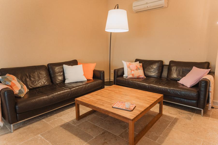 salon avec 2 banquettes en cuir marron, table basse bois clair coussins et plaid