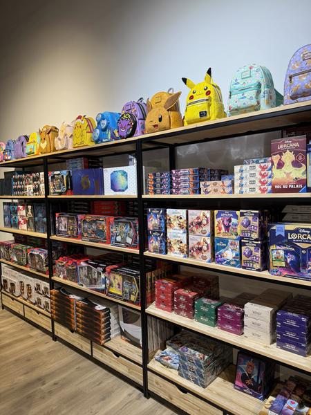 Rayonnages remplis de jeux de cartes, figurines et sacs à dos colorés inspirés de Pokémon et d’autres univers de la pop culture.