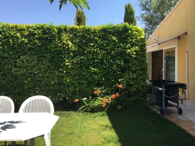 terrasse extérieur dans jardin verdoyant, barbecue sur roulettes et tables et chaises en pvc
