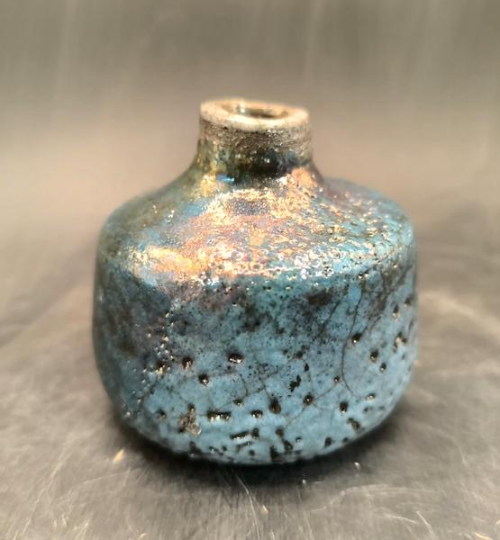 Petit vase en céramique émaillée bleu turquoise, aux reflets métalliques irisés et texture artisanale.