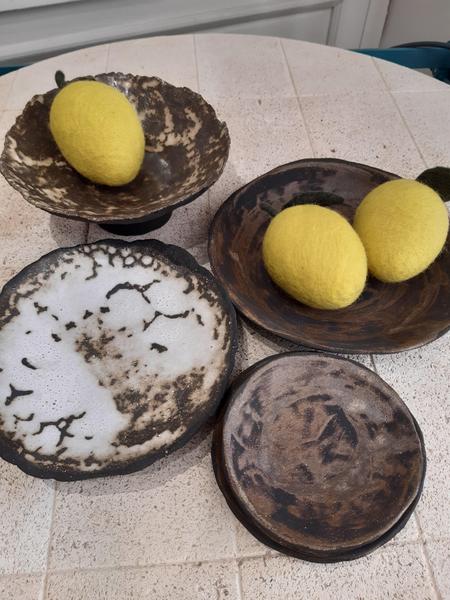 Petites sculptures en céramique claire représentant des silhouettes féminines assises, aux formes douces et épurées.