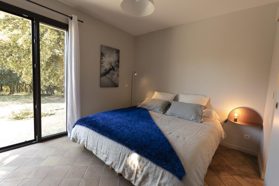 Chambre cosy et récente blanche avec un lit double aux draps bleu roi