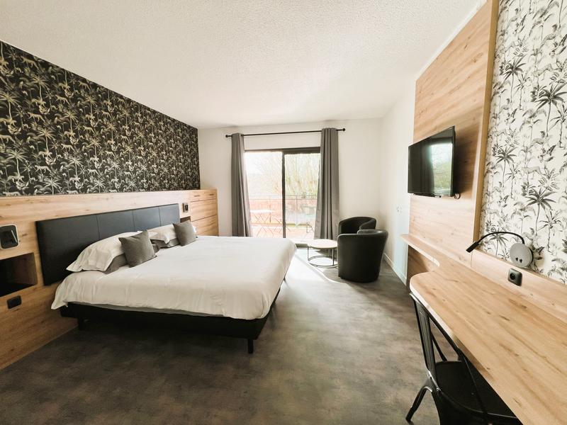 chambre avec mur de paier peint de palmier noir et kaki et lit king size. Mobilier de bois clair