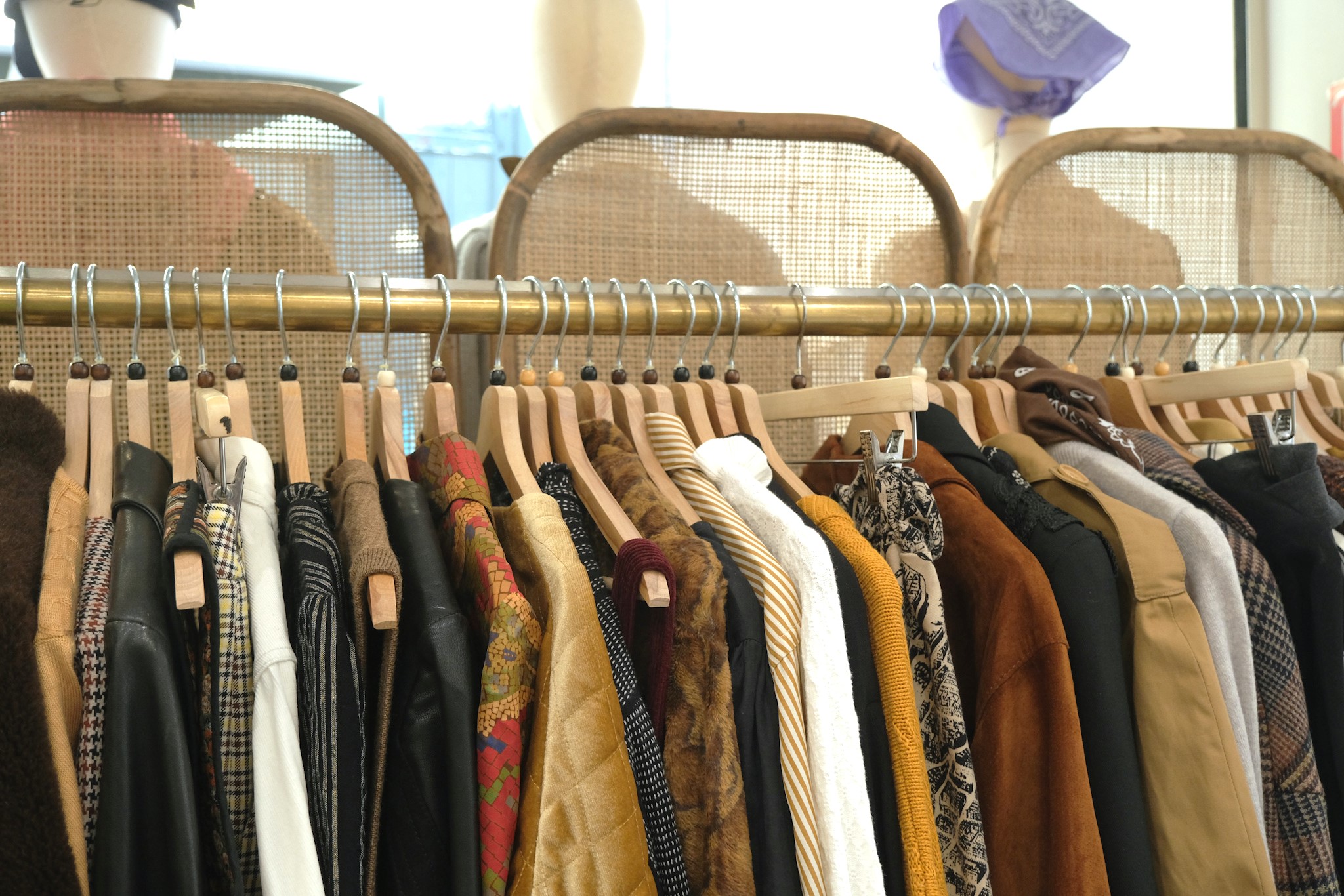 Portants de vêtements soigneusement sélectionnés chez Ex-Aequo Store, mêlant pièces vintage, marques actuelles et articles de seconde main dans une ambiance chaleureuse.