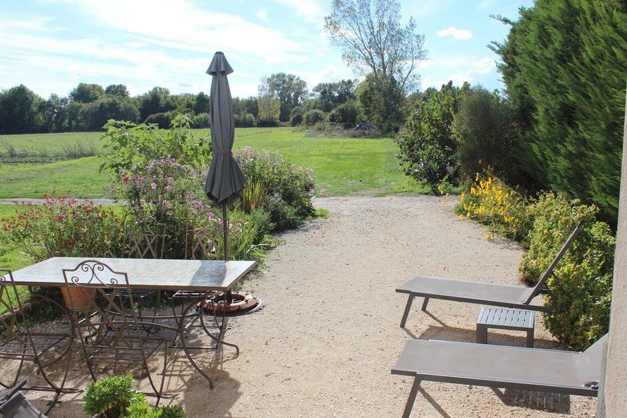 Transats gris avec une table et un parasol dans un grand jardin en campagne