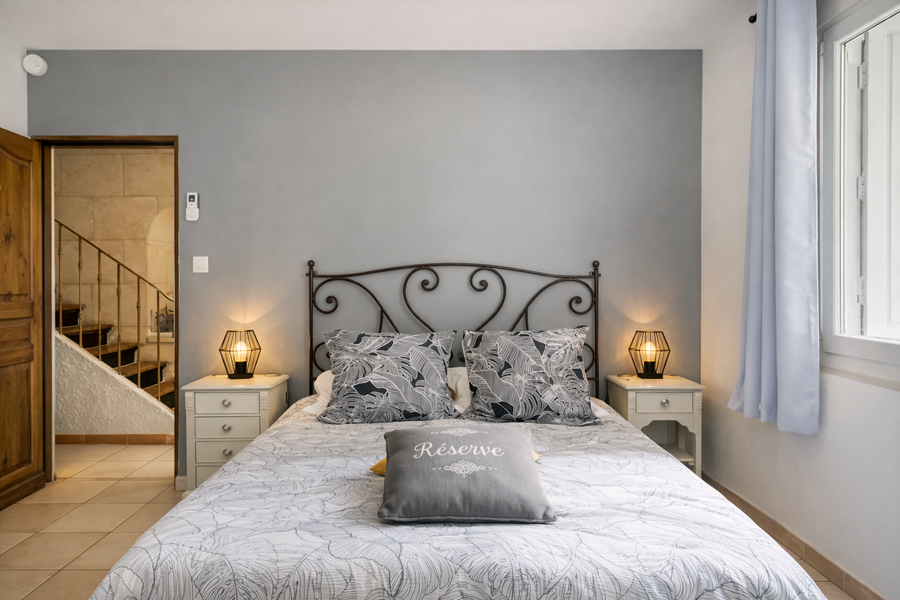 chambre grise avec lit double et tête de lit en fer forgé 