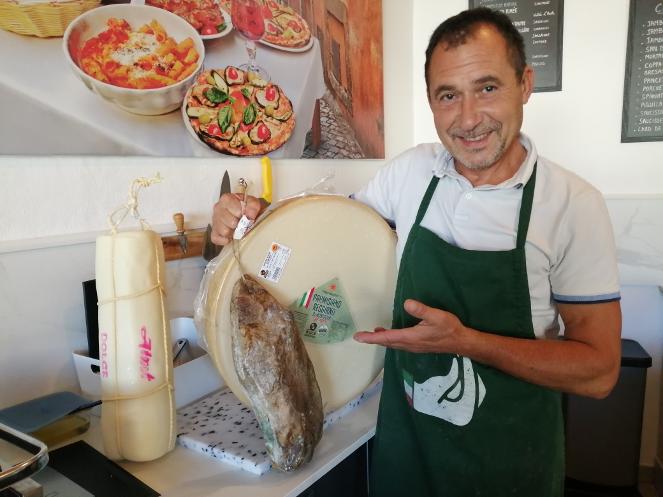 photo du propriétaire devant fromages et charcuterie
