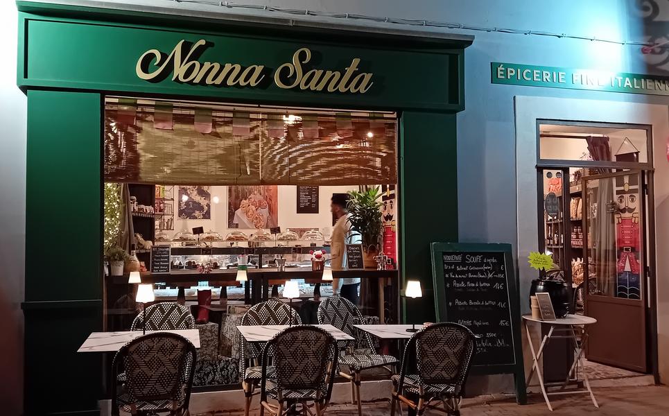 Devanture verte de l'épicerie Nonna Santa avec tables et chaises devant