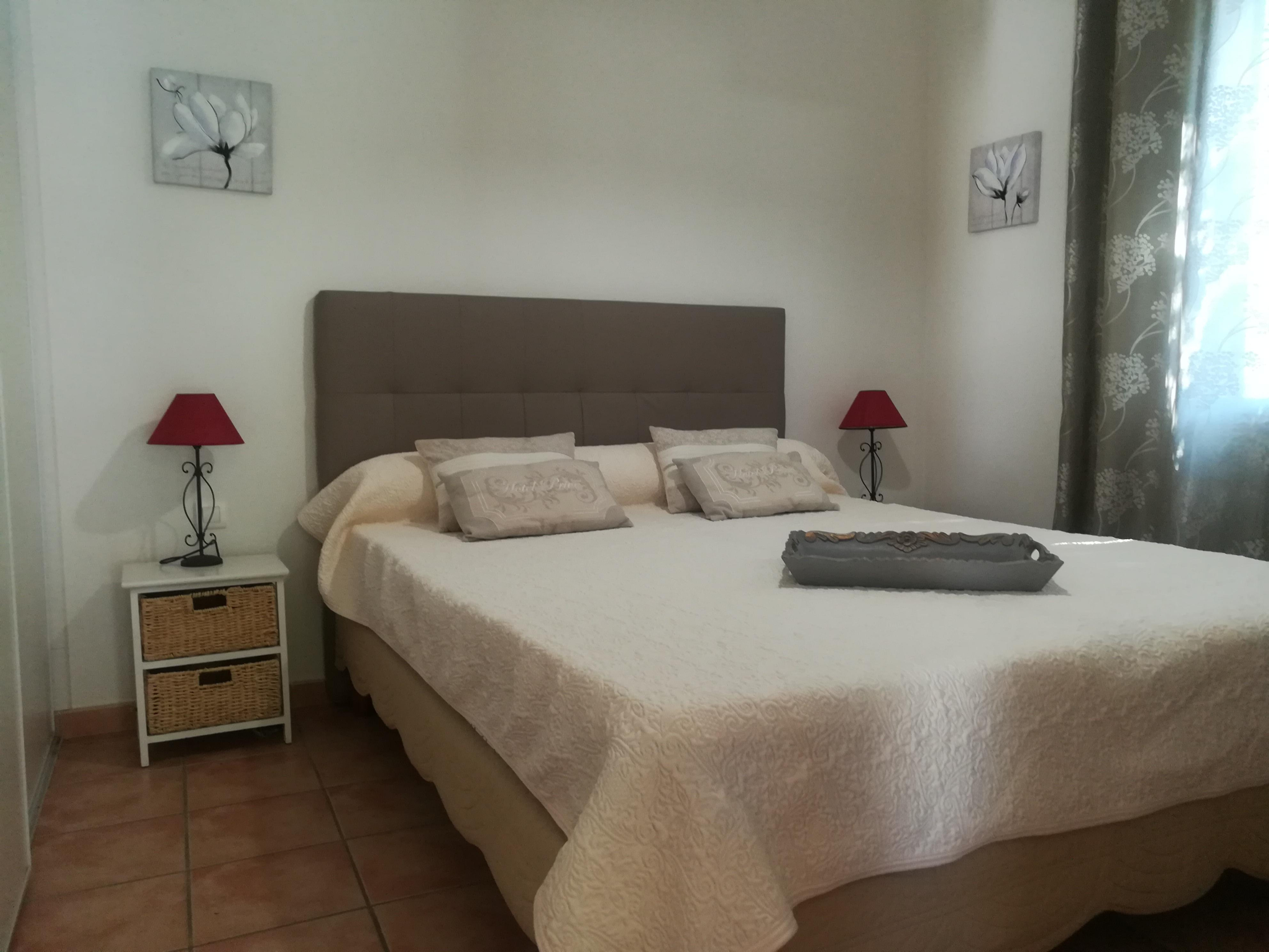 Chambre avec lit double blanche et tête de lit grise 