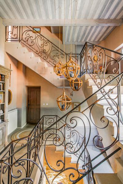 Montée d'escalier en pierre avec rampe en fer forgé et 3 luminaire suspendus 