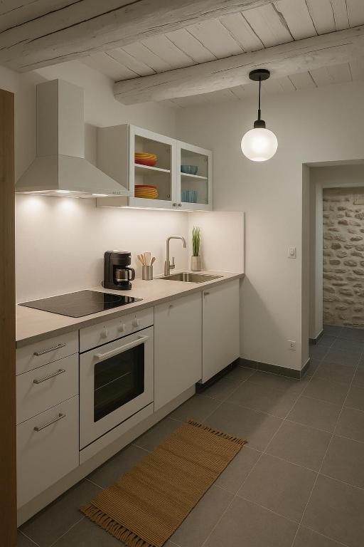 Cuisine moderne et fonctionnelle aux lignes épurées, entièrement équipée pour un séjour en toute autonomie. Les poutres apparentes blanchies apportent une touche provençale chaleureuse à cet espace lumineux et rénové avec soin.