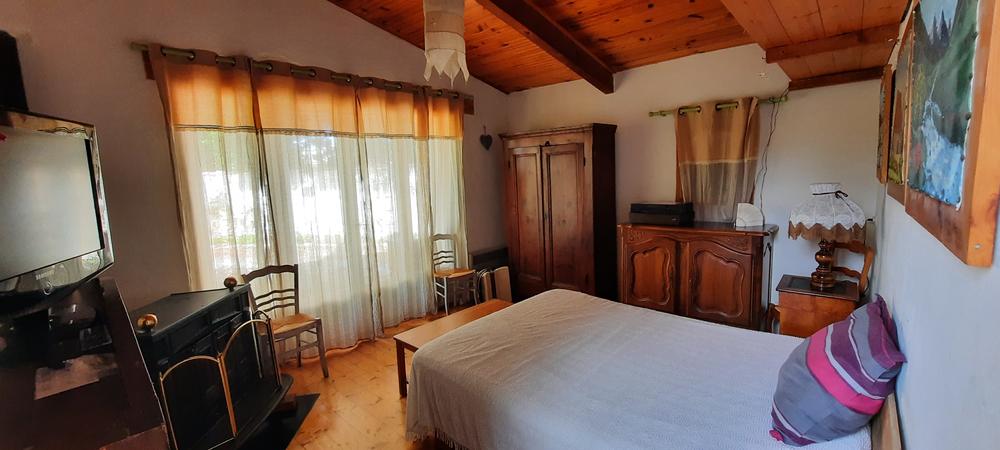 La chambre principale séduit par son ambiance chaleureuse et son mobilier de caractère. Son plafond en bois, ses meubles traditionnels et sa grande baie vitrée apportent charme et luminosité à l'espace. Une pièce confortable, idéale pour se reposer après une journée de découverte dans le Pays des Sorgues et le Luberon.