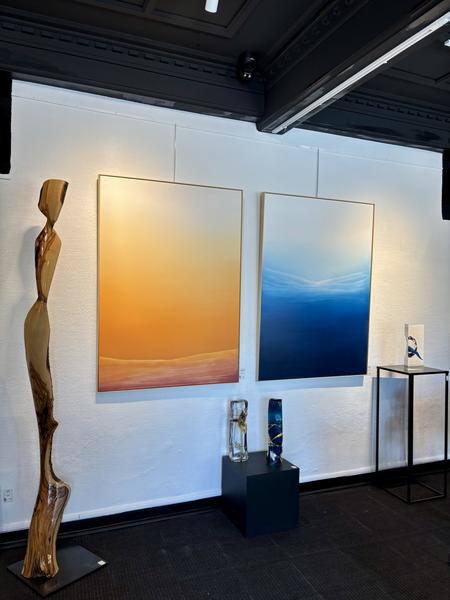 Sculpture en bois avec a son côté droit deux tableaux, l'un orange et l'autre bleu formant un dégradé progressif vers le blanc.