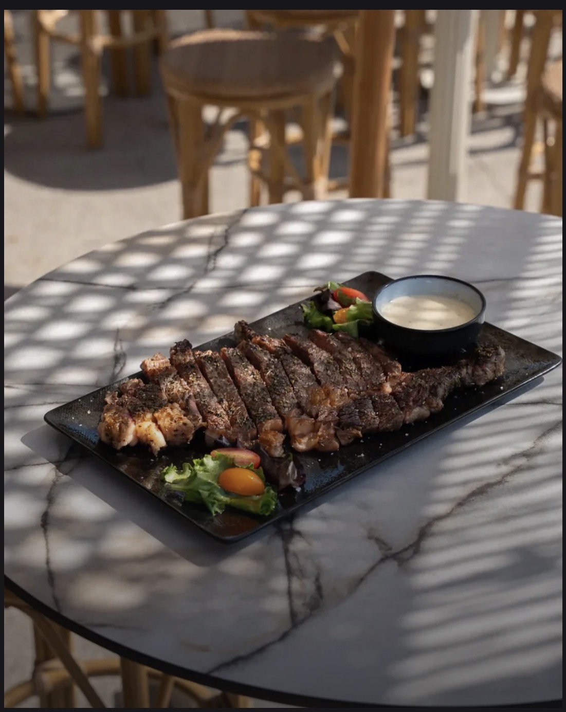 Pièce de viande grillée et tranchée, servie avec salade et sauce, présentée en terrasse chez Via Notte à L’Isle-sur-la-Sorgue.
