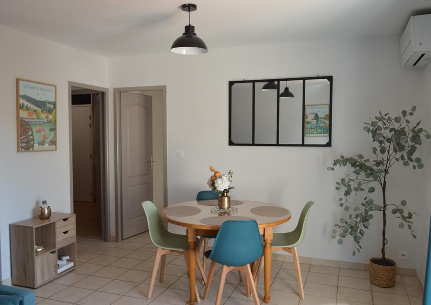 Salon clair avec une verrière et une table ronde avec quatre chaise au milieu de la pièce.