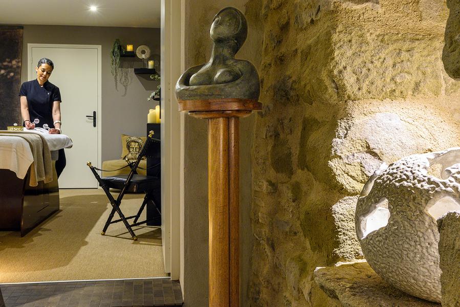 Une cabine de massage à l’ambiance apaisante, mêlant décoration contemporaine, pierres apparentes et atmosphère feutrée.