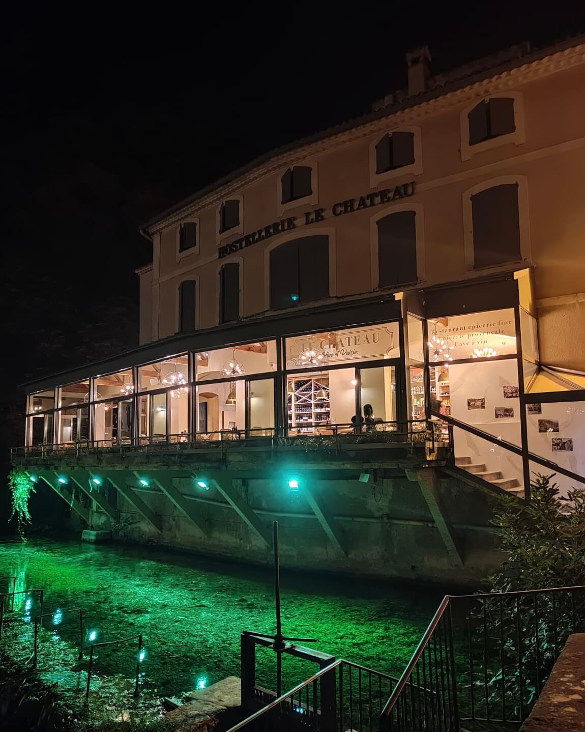 photo de nuit de la devanture de l'établissement, les lumières reflètent l'eau et la couleur des algues