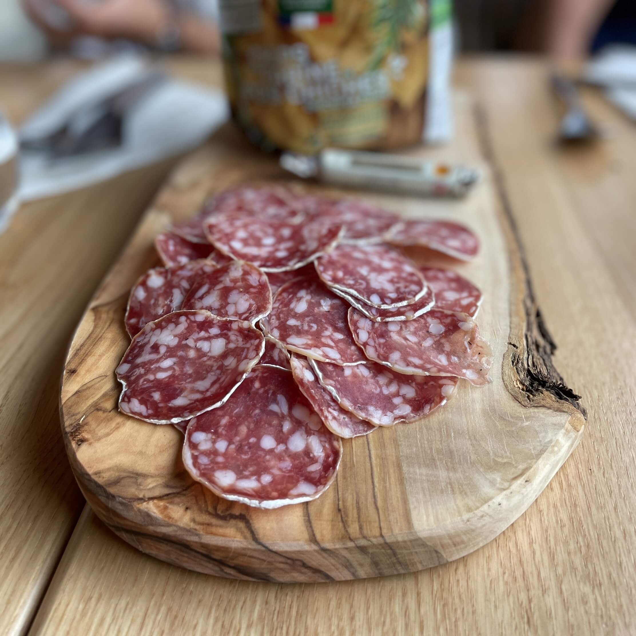 une planche d'olivier sur laquelle sont posées de nombreuses tranches de saucisson