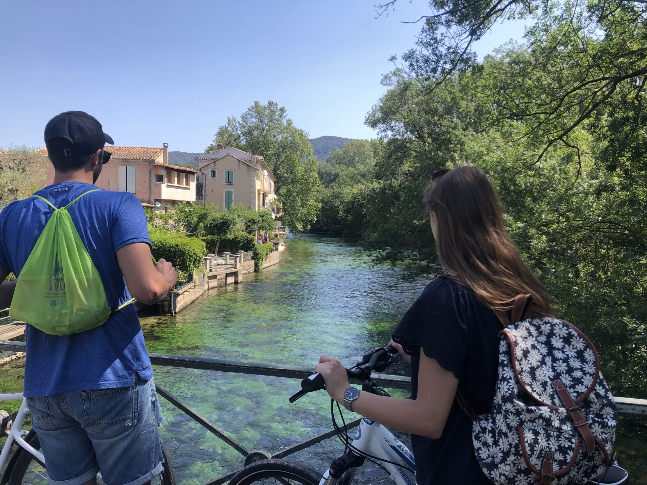 les deux cyclistes prennent une pause pour admirer la Sorgue depuis un pont