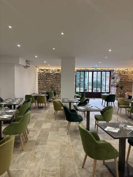 intérieur resto avec mur en pierre et fauteuils verts 