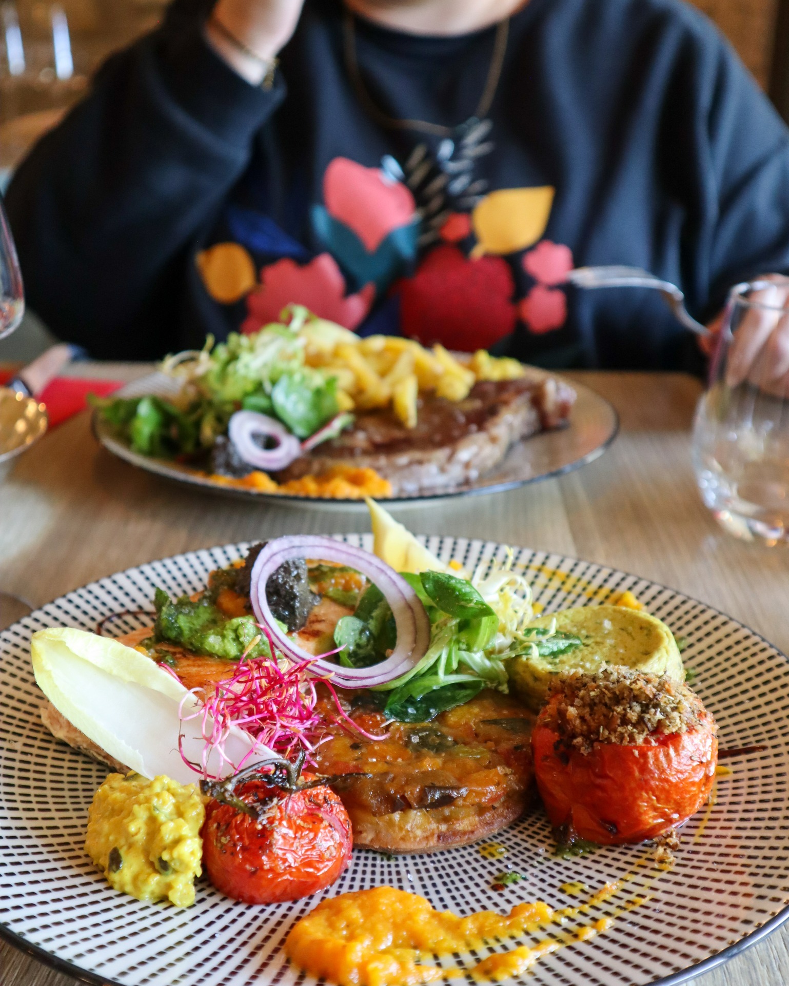 photographie d'une table de deux personnes avec deux assiettes servies, leurs contenus sont variés et colorées, avec des légumes et viandes différentes