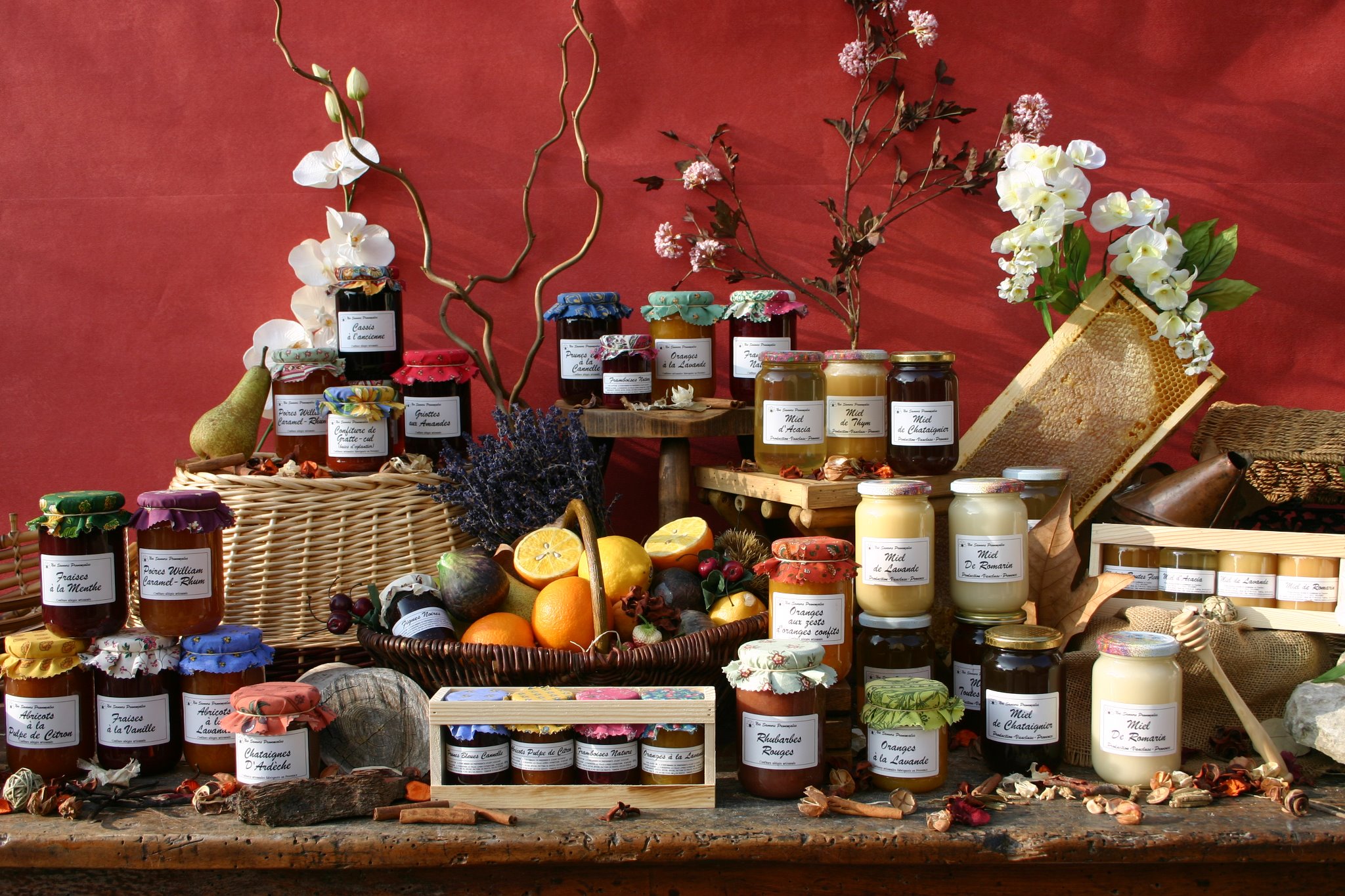 ensemble de produits en bocaux, exposés sur des paniers, avec des fruits, des rayons de ruche et des fleurs