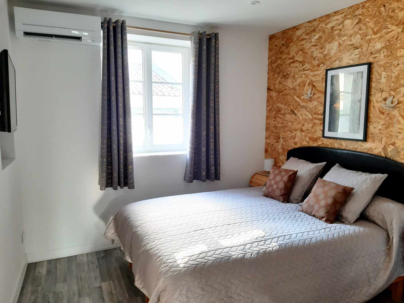Une chambre avec un lit double, un mur en bois et un climatiseur au-dessus d'une fenêtre.