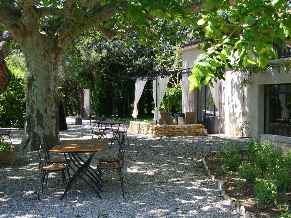 vue du jardin, avec sa table et chaises placées sous l'ombre d'un grand platane