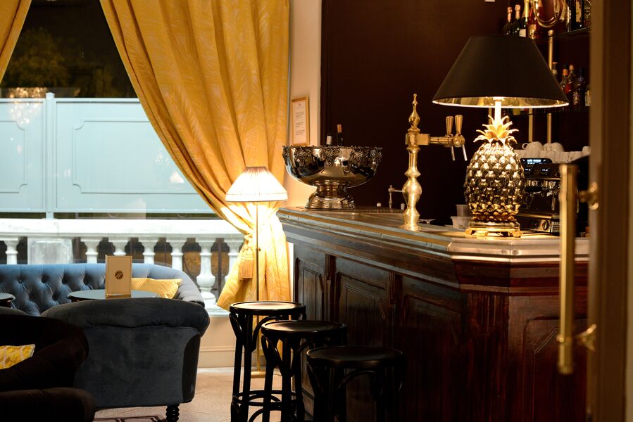 salon avec bar ancien en bois doncé et cuivre fauteuils velours capitonnés bleu et jaune