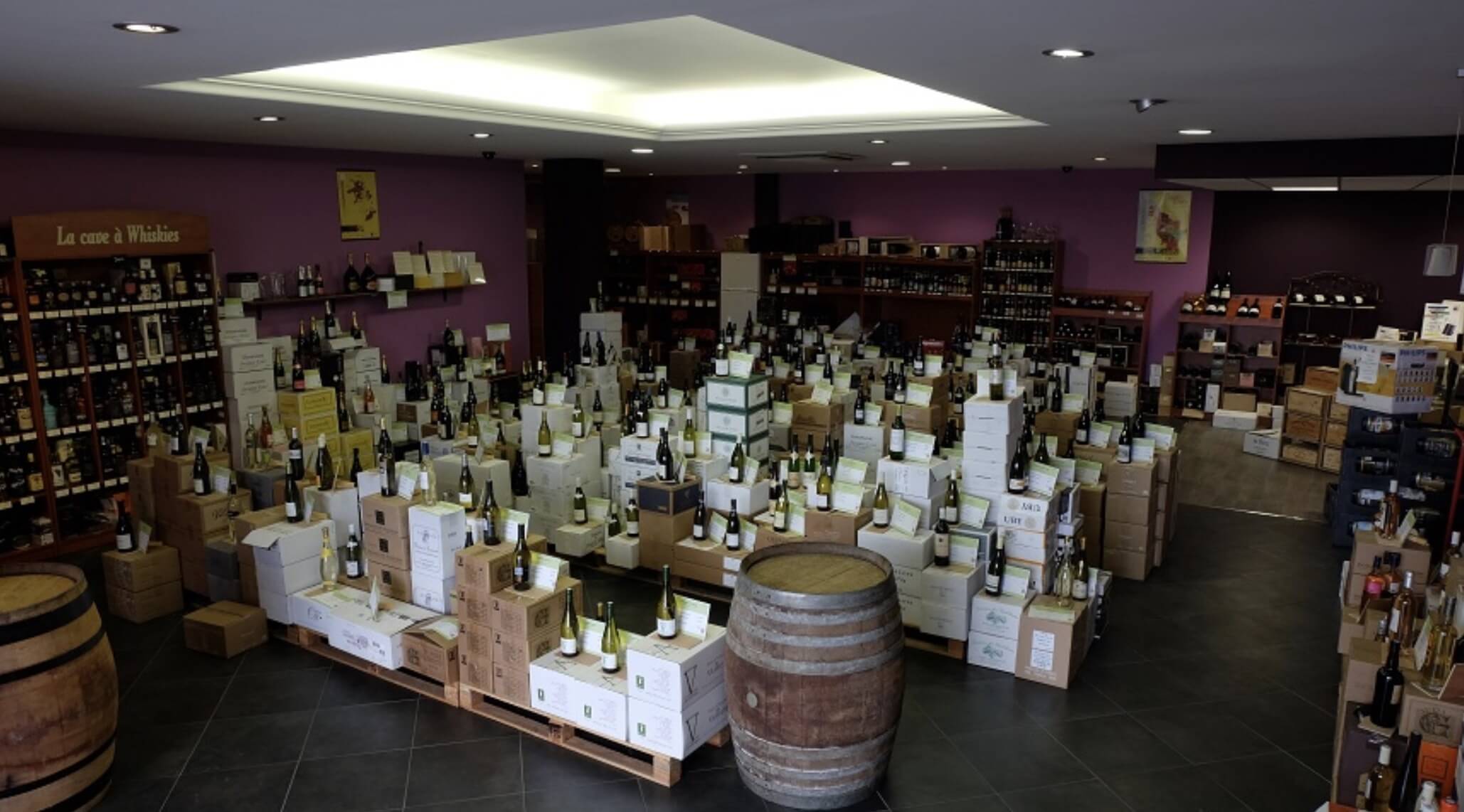 intérieur de la boutique cave, ^résentation de bouteilles sur piles de cartons et un tonneau à vin au premier plan