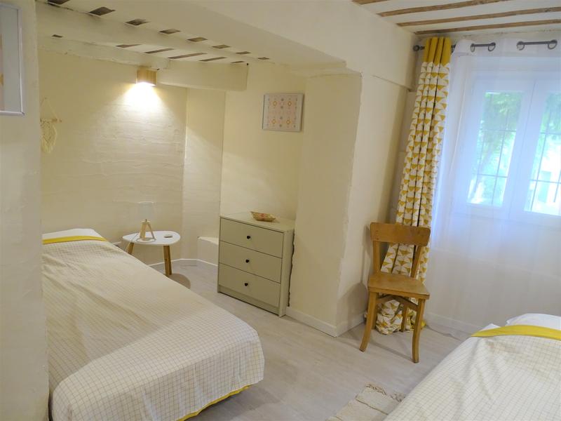 Une chambre avec un lit double, une table de chevet et une lampe, près d'un mur en pierre.