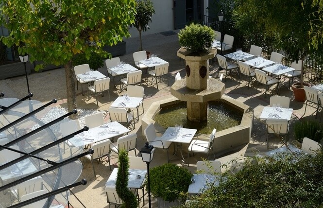 photographie de la cour avec sa fontaine et les tables disposées autour
