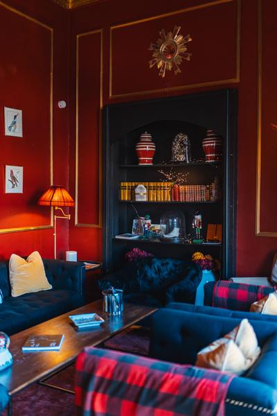 vue du salon avec ses murs rouges, sa bibliothèque et ses fauteuils